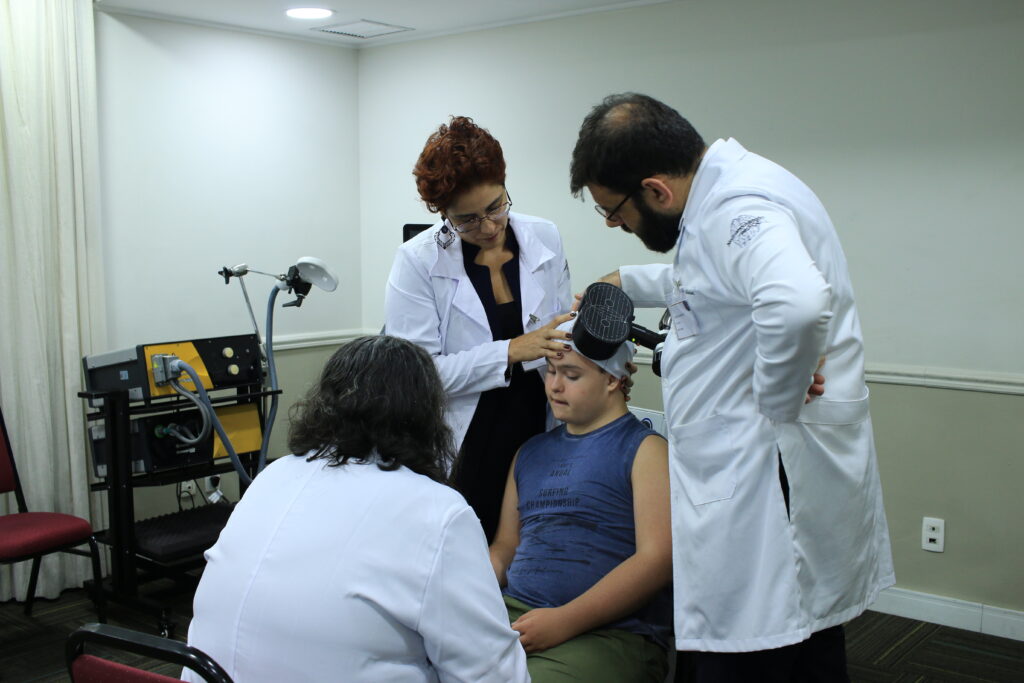 Foto de paciente sendo submetido ao tratamento de Estimulação Magnética Transcraniana (EMT ou TMS), que é a mesma estimulação feita pelo MERT (Magnetic e-Resonance Therapy).